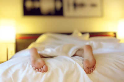 person laying in bed with feet sticking out of covers
