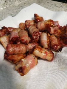 cooked bacon wrapped weenies resting on paper towels to absorb grease